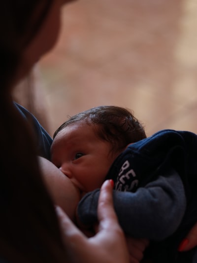 穿黑色连帽衫的妇女抱着穿蓝色连体衣的婴儿